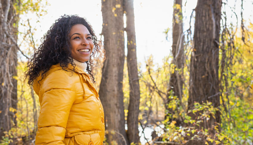 A smiling woman standing in the forest